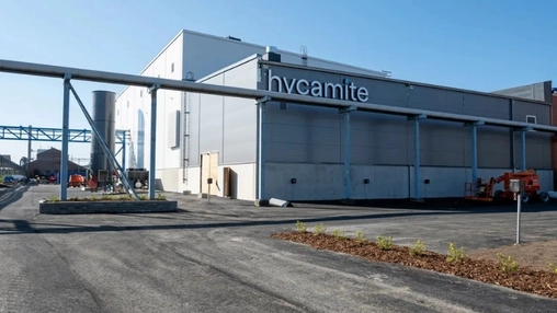 Exterior of the Hycamite industrial plant showing the company logo on a large grey building with pipework