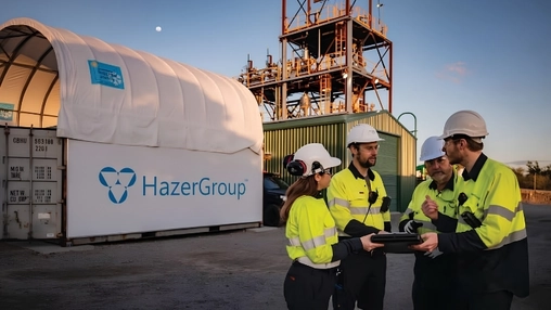 Workers in safety gear discuss operations beside a HazerGroup facility at an industrial site