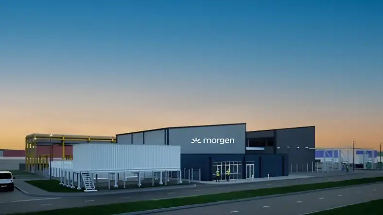 A digital render of a warehouse style plant bearing the morgen logo, set against an orange evening sky